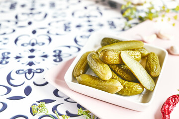 Salted pickled cucumbers preserved canned in glass jar. Plate of pickled homemade gherkins with...