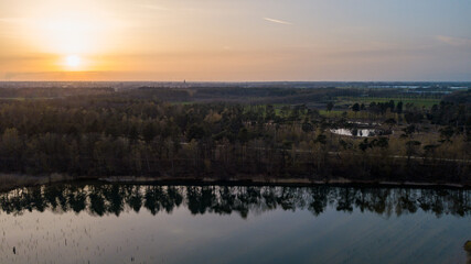 Aerial view shot by a drone of a beautiful dramatic and colorful sunset at coast of the lake. Nature landscape. Nature in Europe. reflection, blue sky and yellow sunlight. landscape during sunrise or