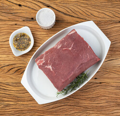 Raw ancho beef, typical argentinian cut, over white plate with seasonings