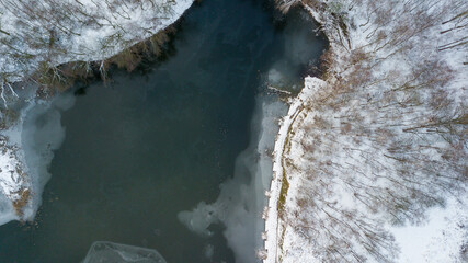 Aerial view of the winter snow covered forest and frozen lake from above captured with a drone. High quality photo