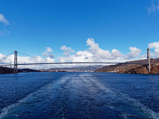 The Full span of the Askoy Suspension Bridge seen from a Vessel departing Bergen Port with its wake centred under the middle of the Bridge.