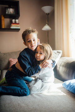 Brother and sister hugging at home.