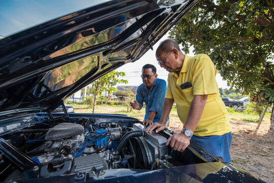 two men looking under the hood of American muscle car in Thailand