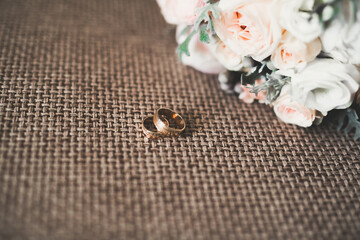 Beautiful toned picture with wedding rings against the background of a bouquet of flowers