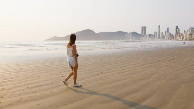 Image of tourist woman walking at Balneário Camboriú beach, Brazil.