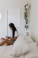 Young adult woman drinking coffee in bed