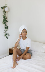 Filipino woman sitting on bed drying her hair