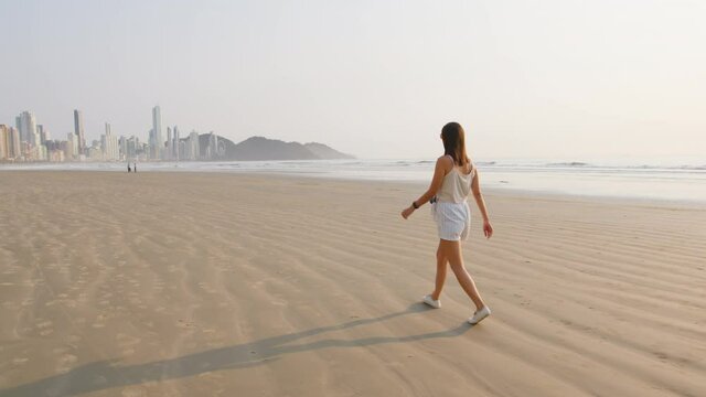 Image of tourist woman walking at Balneário Camboriú beach, Brazil.