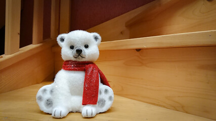 A figure of a polar bear with a red scarf stands on wooden sticks