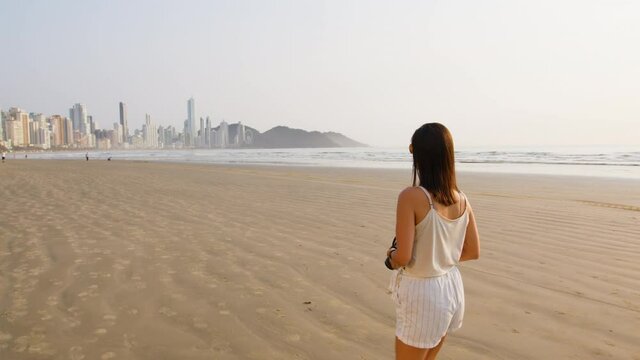 Image of tourist woman photographing at Balneário Camboriú beach, Brazil.
