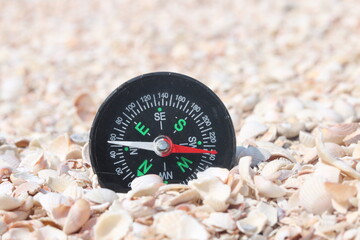 Classic navigation compass on beach as symbol of tourism with compass, travel with compass and...