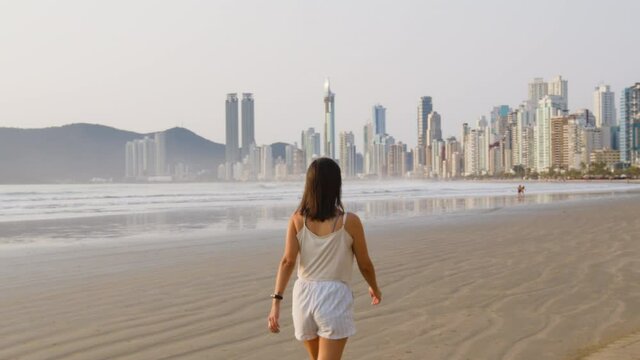 Image of woman walking at the beach early morning, Balneário Camboriú, Brazil.