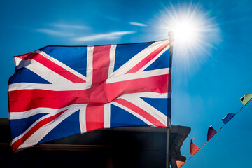 Fototapeta na wymiar Brilliant sunshine behind Great Britain flag and bunting