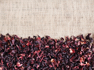 Straw mat background with dry hibiscus tea, closeup. Flat lay, top view.