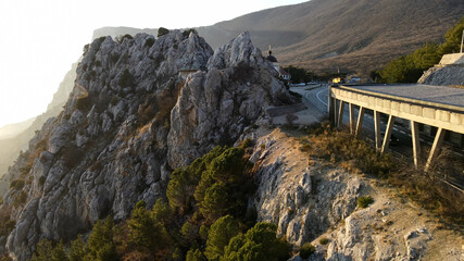 A steep cliff next to the road. A steep mountain against a clear sky. A mountain peak.