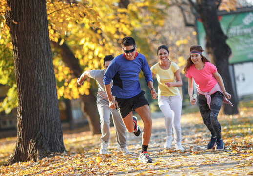 A group of young friends enjoys an invigorating jog in the park during a crisp autumn afternoon, surrounded by vibrant foliage.Autumn concept.