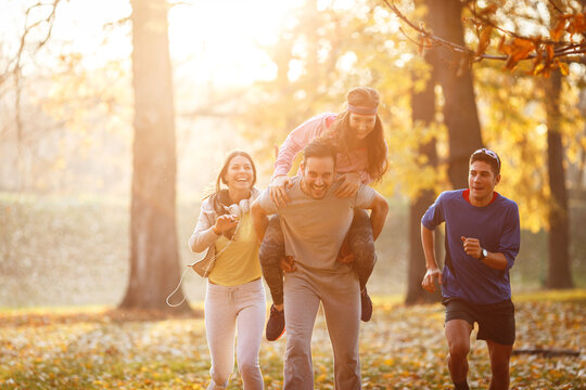 A group of young friends has a great time at the park during a crisp autumn day, surrounded by vibrant foliage and filled with laughter and fun.