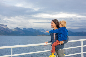 Child and mom, cute blond boy with mother, looking at the mountains from a ferry in Nortern Norway...
