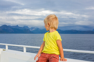 Child, cute boy, looking at the mountains from a ferry in Nortern Norway on his way