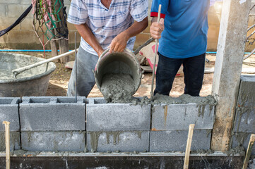 masonry worker make concrete wall by cement block and plaster at construction site