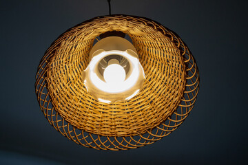 Beautiful lamp on the ceiling with a wooden wicker lampshade