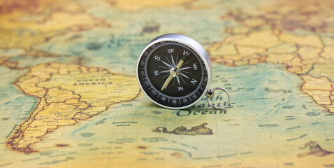 Fototapeta na wymiar Classic round compass on background of old vintage map of world as symbol of tourism with compass, travel with compass and outdoor activities with compass
