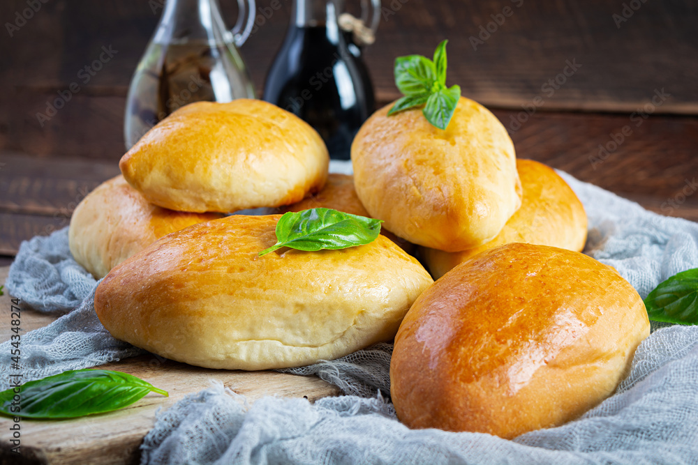 Wall mural Traditional Russian cabbage pies on wooden background. Baked homemade pirozhki with cabbage