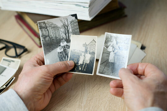 closeup male hand holding old vintage photos of 1940-1950, concept of family tree, genealogy, childhood memories, memory of ancestors