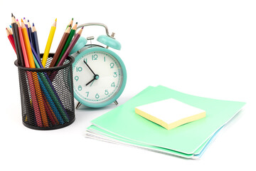 School items. Alarm clock, notebooks, pencils for drawing on a white background. Concept of education, back to school, creativity and learning. Copy space.