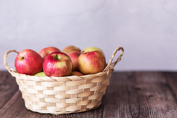 Basket with red apples on a wooden background