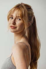 Naklejka premium Close-up portrait of young beautiful tanned woman without makeup isolated over gray studio background. Natural beauty concept.