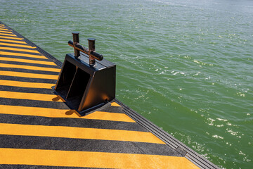 Close-up of an orange and black quay with a large metal mooring bollard for the ferry boats or vaporetto in the Venetian lagoon, Venice, Veneto, Italy, Europe.