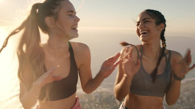 funny girl friends dancing on mountain top celebrating successful hiking adventure with victory dance 