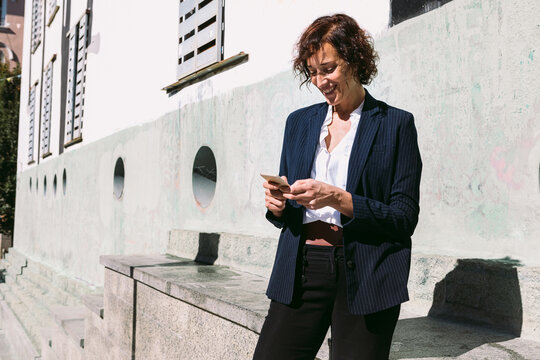 Smiling woman in formal wear browsing on smartphone