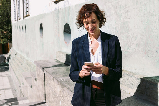 Smiling woman in formal wear browsing on smartphone
