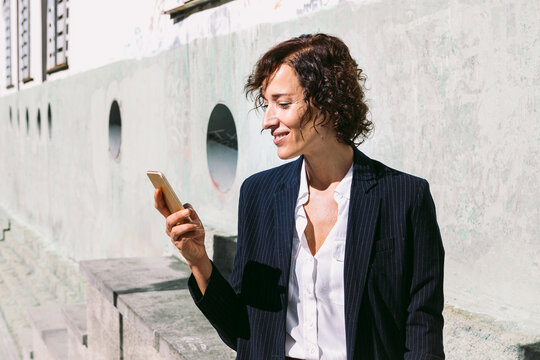 Smiling woman in formal wear browsing on smartphone