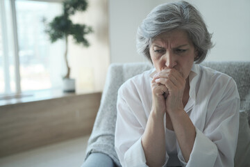 A thoughtful older woman, alone at home considering a dangerous health problem. Upset senior single...