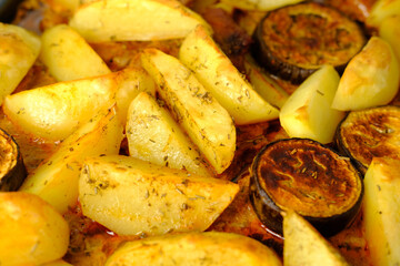 appetizing potatoes, eggplant slices baked in the oven, lying on a baking sheet, the concept of home cooking, traditional dishes