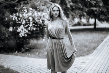 Contrasting black and white portrait of a sexy glamorous girl in a hat and dress in nature. With film grain, noise