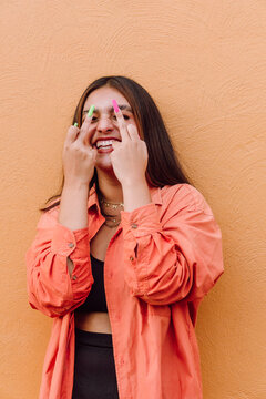 Expressive woman showing fuck gesture against orange wall