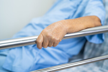 Asian senior or elderly old woman patient lie down handle the rail bed with hope on a bed in the hospital.