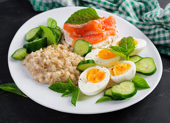 Breakfast oatmeal porridge with boiled eggs, salmon sandwich and cucumbers salad. Healthy food. Lunch.