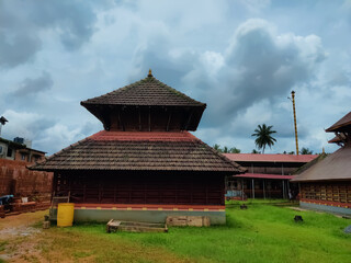 Fototapeta na wymiar Addor Temple ancient Kerala architecture view under the sky. Beautiful design temple carvings surrounded by green grasses