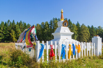 White Buddhist Stupa of an Enlightenment decorated with colorful tibetan buddhist prayer scarves...