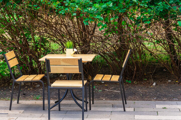 Obraz premium Table and chairs with grass in a decorative watering can under the open sky.