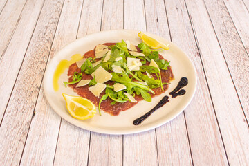 Plate of fine Italian beef carpaccio with parmesan cheese slices, olive oil, balsamic vinegar,...