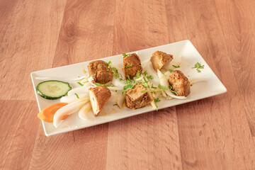 lamb tikka masala skewer with raw white onion, coriander and parsley on a white tray