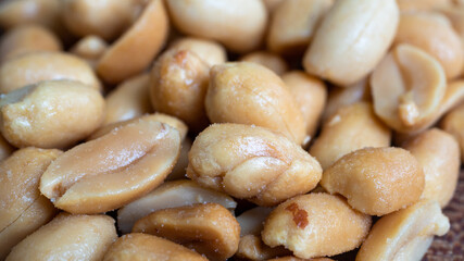 Amazing close up of salted peanuts in a pile. The peanuts are sweating heavily from the high...
