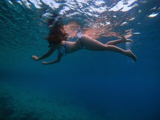 Mujer nadando bajo el agua en vestido de baño