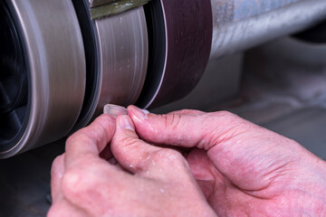 Craftsman preforming white transparent gemstone into the oval cabochon form